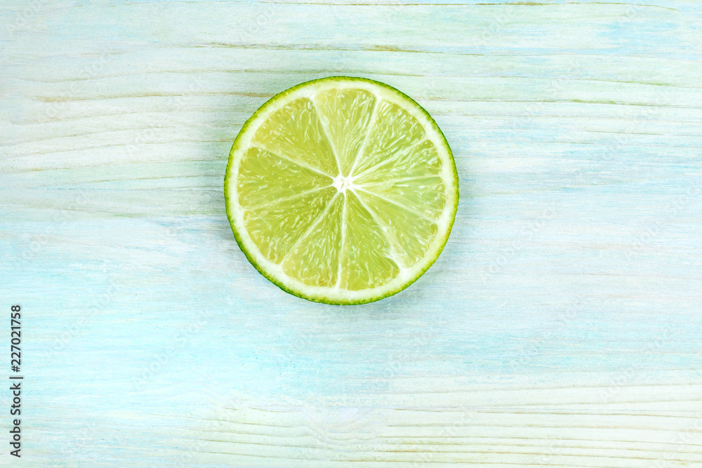An overhead photo of a single lime slice on a teal blue background with copyspace An overhead photo of a single lime slice on a teal blue background with copyspace