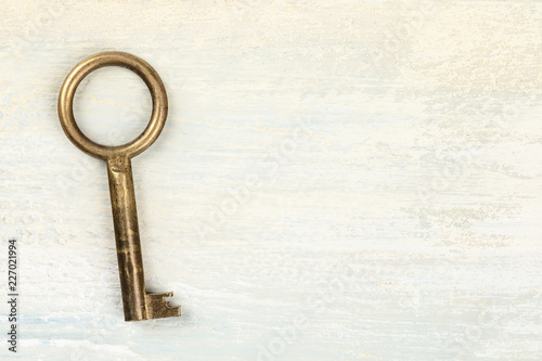 An overhead photo of an old key, on light background with copy space