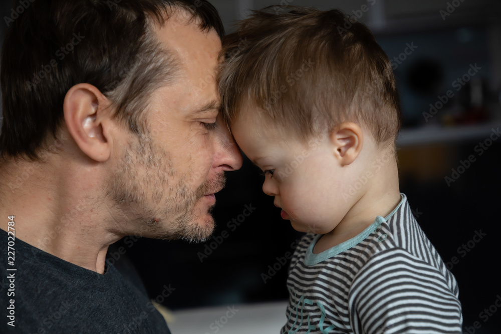 Cute boy with Down syndrome playing with dad on in home living room Cute boy with Down syndrome playing with dad on in home living room
