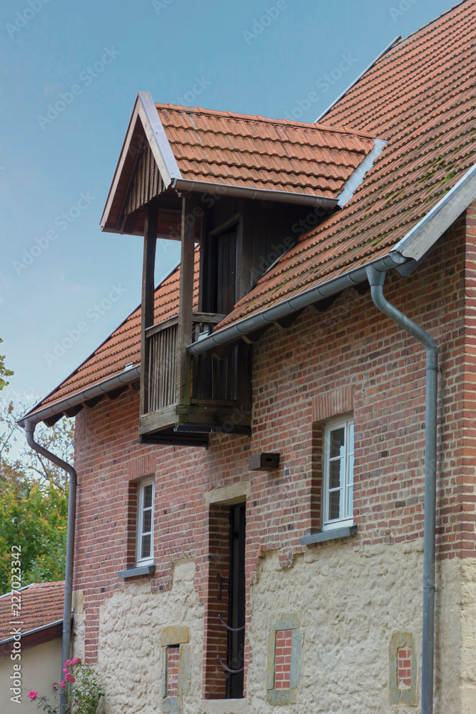 Backsteinhaus mit Gaube und Balkon aus Holz