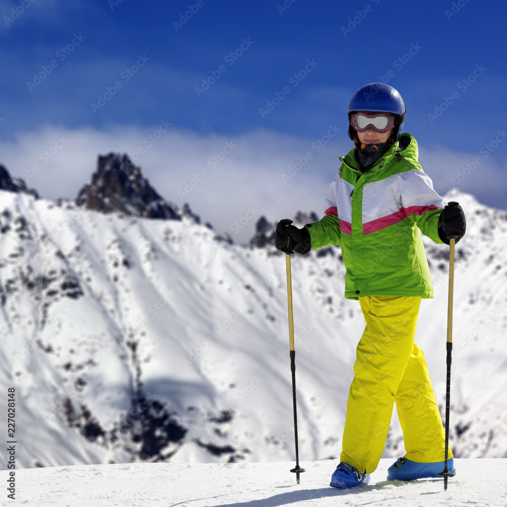Young skier with ski poles in snowy mountains at sun winter day
