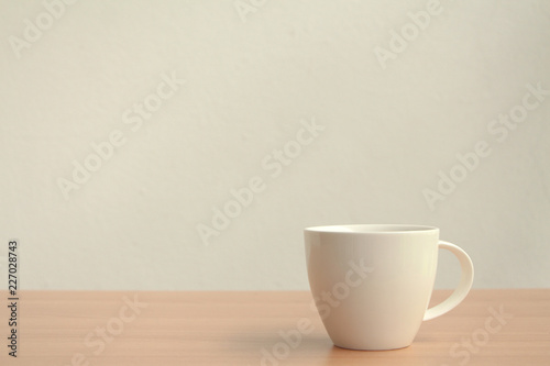 White coffee cup on wood table with copy space on white wall background.