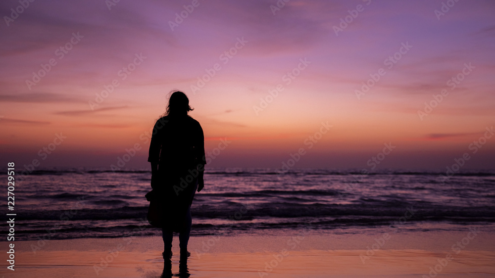 Woman standing in beach at sunset