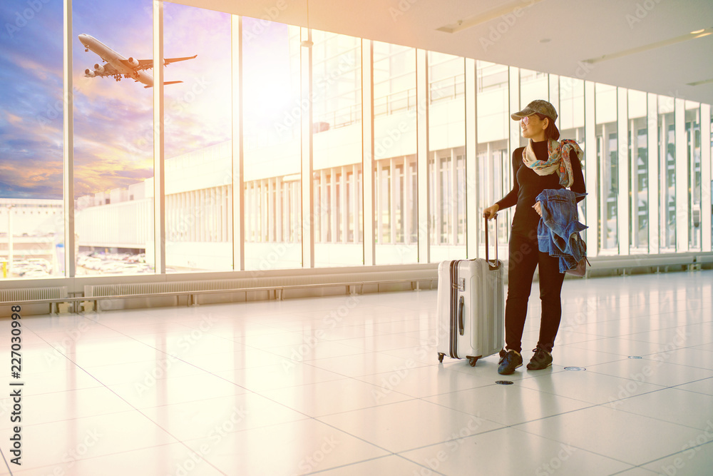 single woman and traveling luggage standing in airport terminal building
