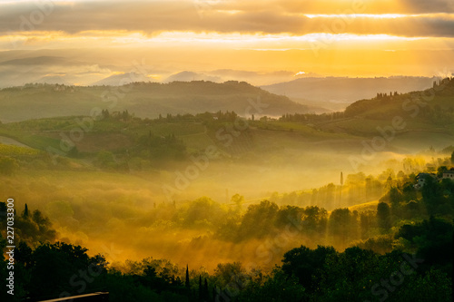 Dawn in a misty valley in the hills in Tuscany, Italy