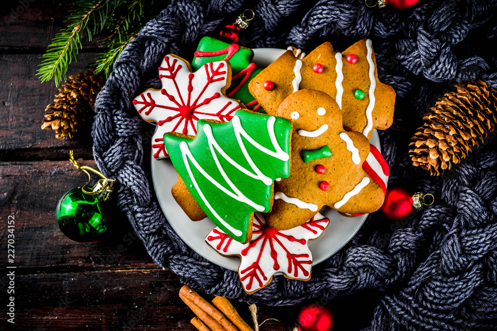 Traditional christmas sweet treats, colorful sugar glazed homemade gingerbread cookies with xmas tree, decoration, spices and coffee latte mud on classic wooden background copy space top view