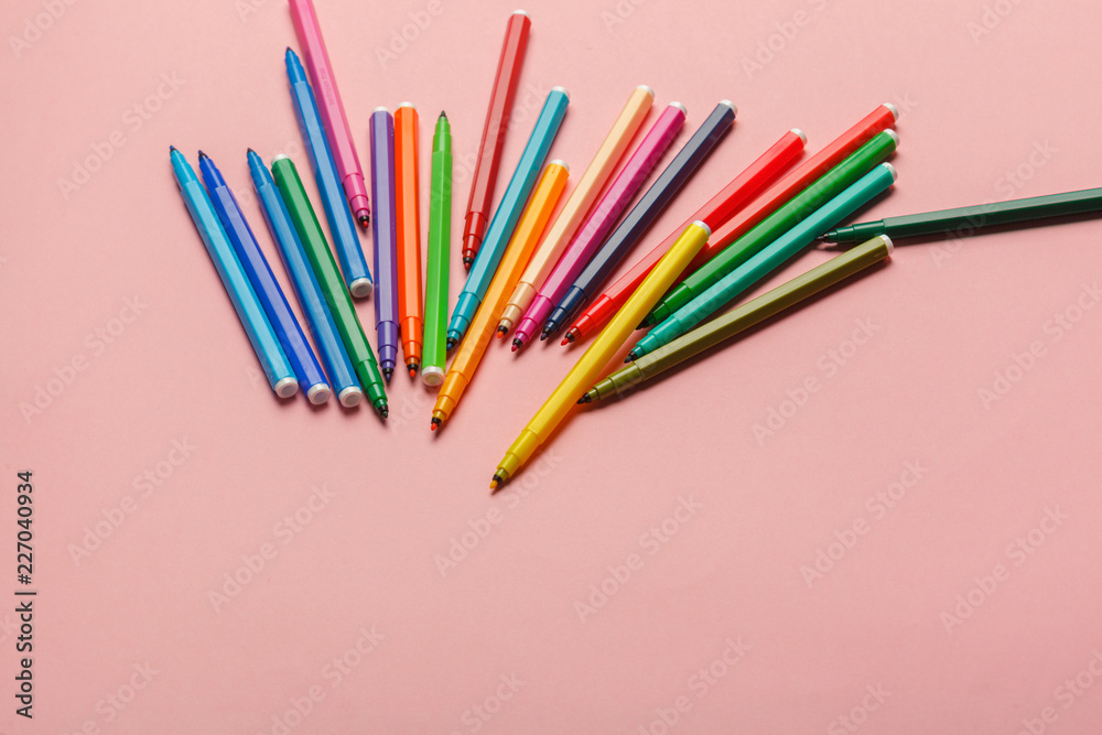 Assortment of colorful felt tip pens on pastel pink background