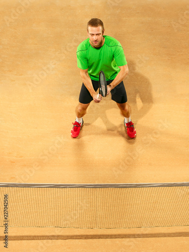 I am saving this ball now. Player lunge, game of defense. The one caucasian fit man playing tennis at the earthen court . Player jumping in full length with racquet and ball. Emotions on face. Upper