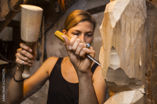Sculptress carving wooden figure photo