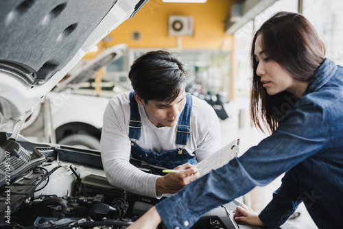 Reliable auto mechanic talking to a female customer the engine error in a modern automobile repair shop