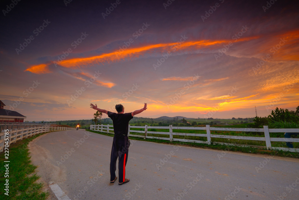 Fototapeta premium Successful man raising arms after cross track running on sunrise. Fitness male athlete with arms up celebrating success and goals after sport exercising and working out.