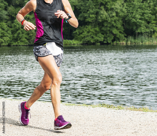 Female runner racing 10K on a trail around a lake