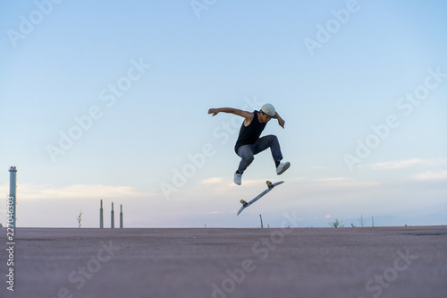 Young man doing a skateboard trick on a lane at dusk © Westend61