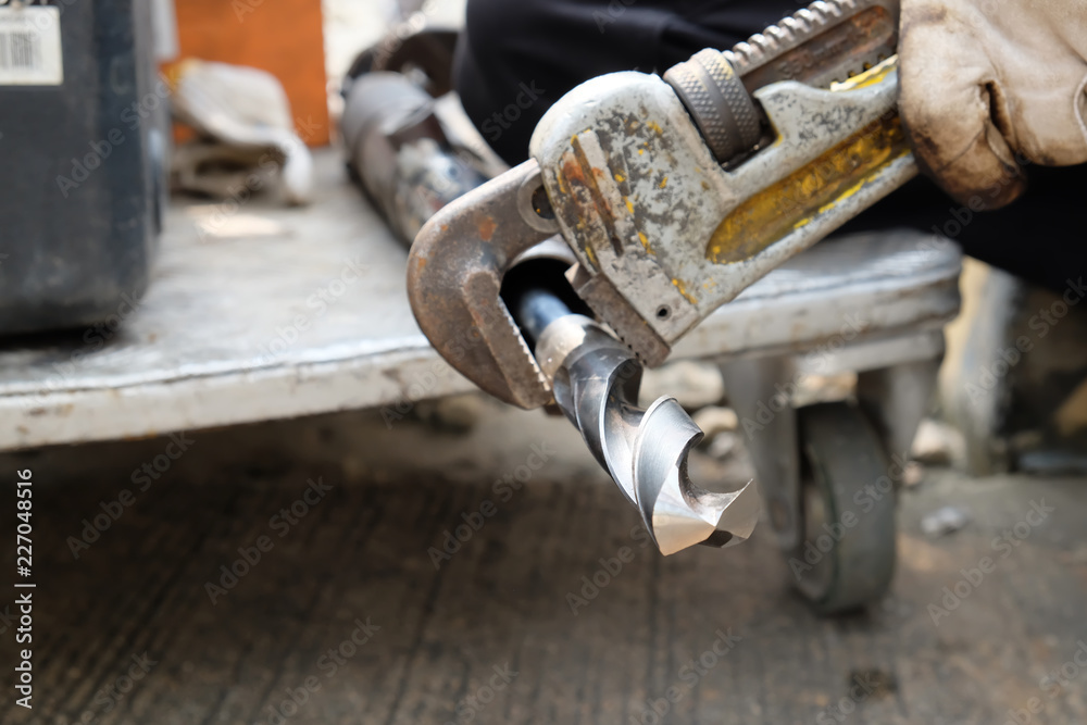 Work with a wrench holding a drill bit. Work with a wrench holding a drill bit.