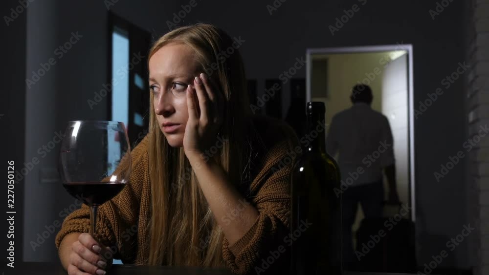 Rejected betrayed pretty woman with glass of wine sitting in deep depression and offense at home after finding out that husband cheating her. Cheating man moving out of house after family conflict.