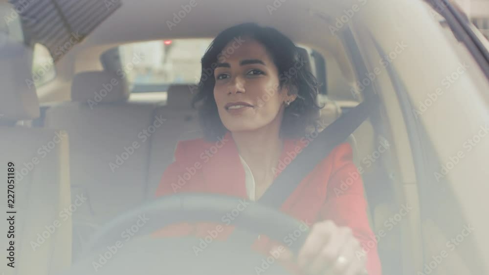 Portrait of Beautiful Young Woman Driving Car through Sunny Suburban Area. Camera Shot Made From the Front Windshield.