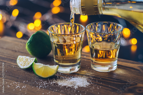 Shot of tequila with lime and salt on bokeh background