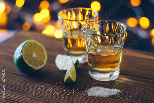 Shot of tequila with lime and salt on bokeh background