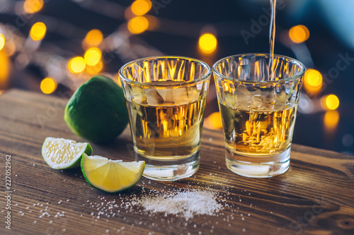 Shot of tequila with lime and salt on bokeh background