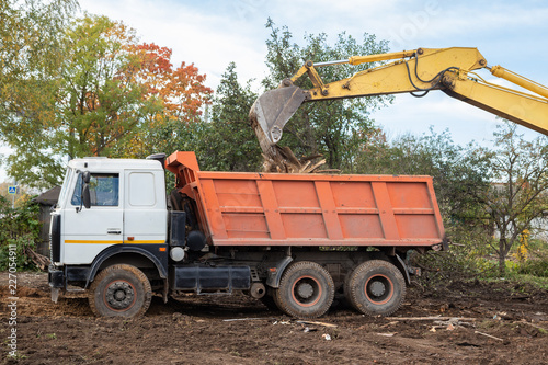 Excavator bucket loading construction debris into truck body closeup