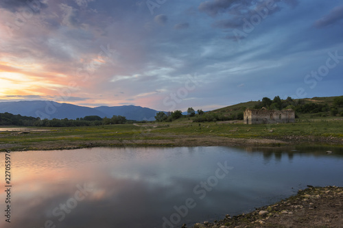 Colorful, spectacular sunset over Balkan mountain, artificial lake Jrebchevo and abandoned, ruined church. Last rays of light. Landscape, background.