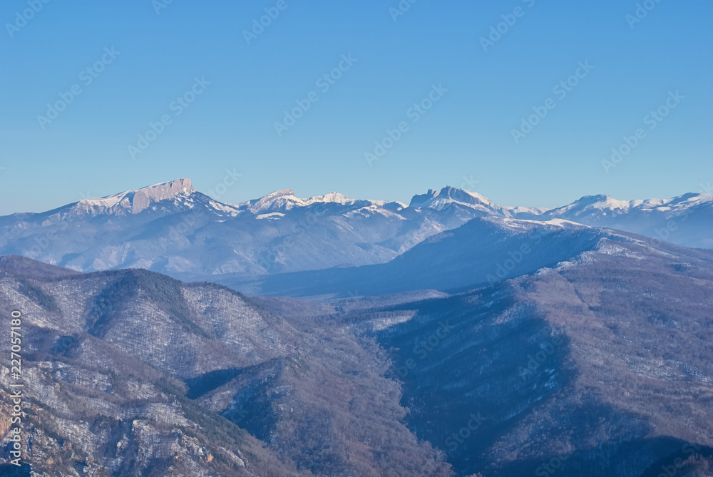 Mountain landscape. On the front and middle ground there is a forest, behind the snow-covered peaks of the mountains. Beautiful blue sky. Lago-Naki, The Main Caucasian Ridge, Russia