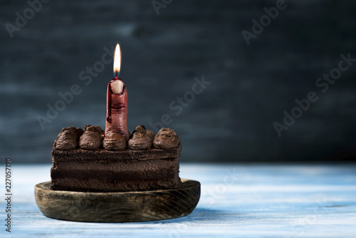 bloody middle finger with a lit wick on a cake