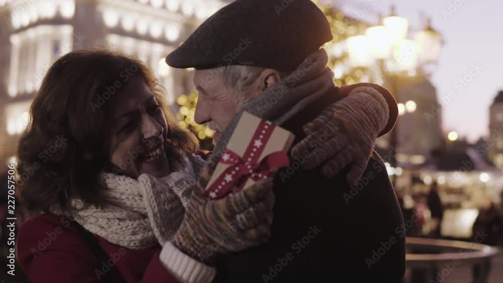 Senior man giving a present to an overjoyed woman on an outdoor Christmas market. Senior man giving a present to an overjoyed woman on an outdoor Christmas market.