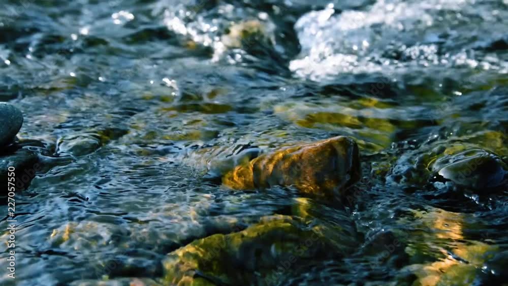 Motorised dolly slider shot of the splashing water in a small mountain river near forest. Huge wet rocks and sun rays. Horizontal steady movement at rural scene. Motorised dolly slider shot of the splashing water in a small mountain river near forest. Huge wet rocks and sun rays. Horizontal steady movement at rural scene.