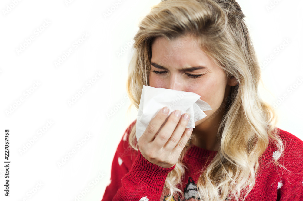 Symptoms of flu or allergies. Strong young European woman with fever, sneezing in a tissue, allergy, cold, with copy space, young girl, portrait of a sick woman, isolated on a white background. Symptoms of flu or allergies. Strong young European woman with fever, sneezing in a tissue, allergy, cold, with copy space, young girl, portrait of a sick woman, isolated on a white background.