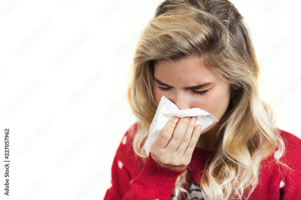 Symptoms of flu or allergies. Strong young European woman with fever, sneezing in a tissue, allergy, cold, with copy space, young girl, portrait of a sick woman, isolated on a white background. Symptoms of flu or allergies. Strong young European woman with fever, sneezing in a tissue, allergy, cold, with copy space, young girl, portrait of a sick woman, isolated on a white background.