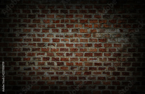 Background and Wallpaper or texture which has dim light of dark discolored old brick wall ancient vintage retro style have damage and cracks.
