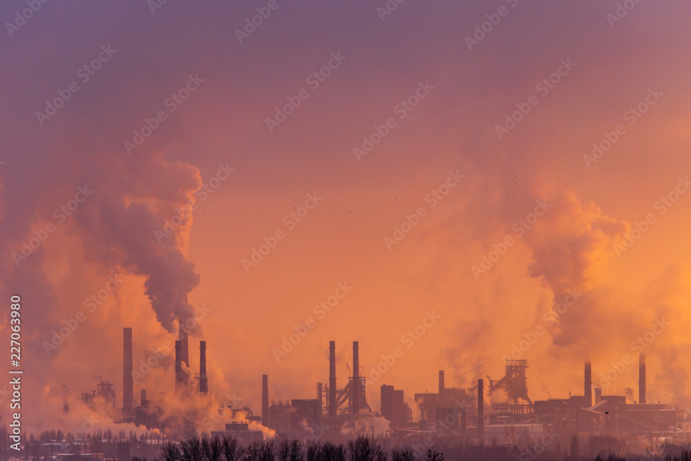 Smoke from the factory pipes against the dawn of the sun