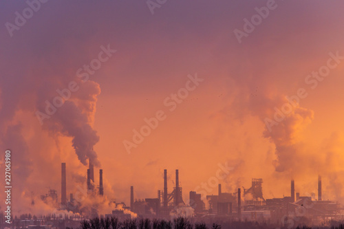 Smoke from the factory pipes against the dawn of the sun