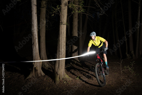Obraz na płótnie Man riding a mountain bike at night with lights. w salonie
