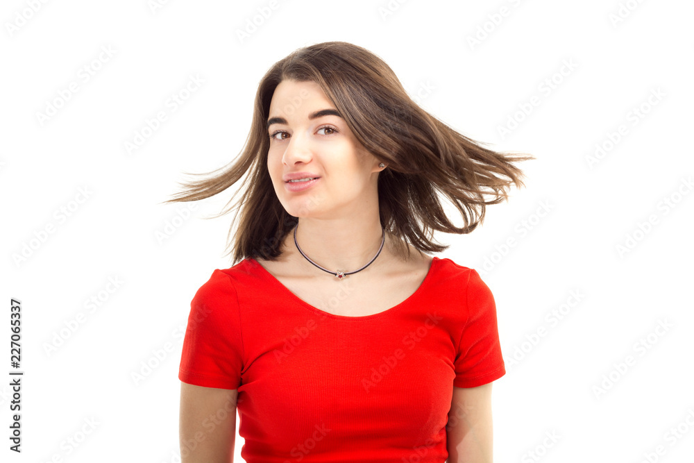 Closeup portrait of a young happy smiling girl in red t-shirt, wind blows her hair against white background Closeup portrait of a young happy smiling girl in red t-shirt, wind blows her hair against white background