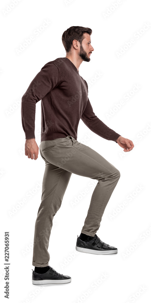 An isolated bearded man in casual wear steps up with one leg in a side view on a white background. An isolated bearded man in casual wear steps up with one leg in a side view on a white background.