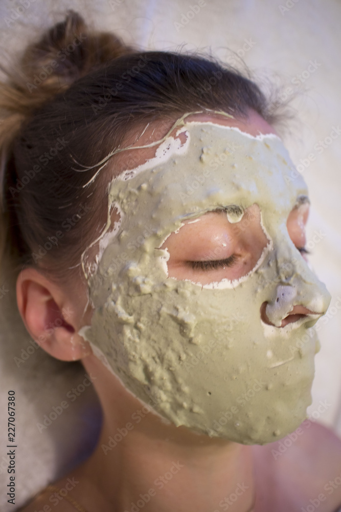 Naklejka premium Spa Woman applying Facial clay Mask. Beauty Treatments. Close-up portrait of beautiful girl applying facial mask.
