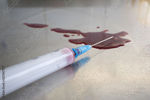 syringe with blood and a puddle of blood on the medical table photo