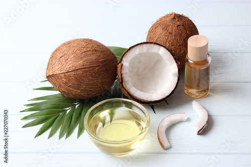 coconuts and coconut oil with tropical leaves on a wooden background photo