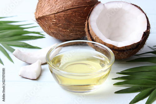 coconuts and coconut oil with tropical leaves on a wooden background