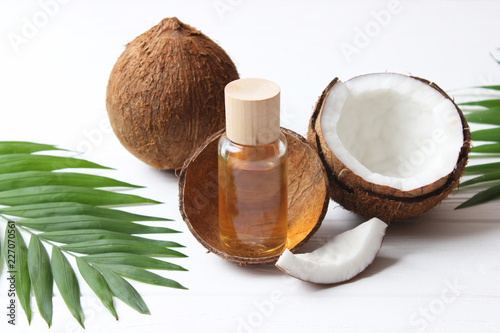 coconuts and coconut oil with tropical leaves on a wooden background