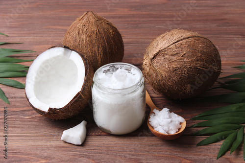 coconuts and coconut oil with tropical leaves on a wooden background
