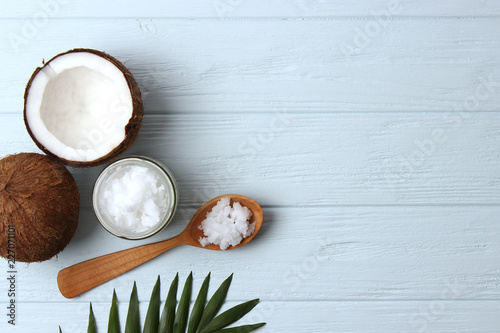 coconut oil, coconuts and green tropical leaves on wooden background. Top view.