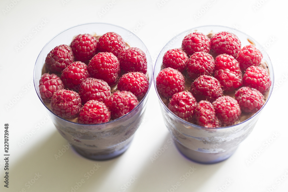 a hand with a beautiful manicure holds a cake in a Cup with berries and chocolate a hand with a beautiful manicure holds a cake in a Cup with berries and chocolate