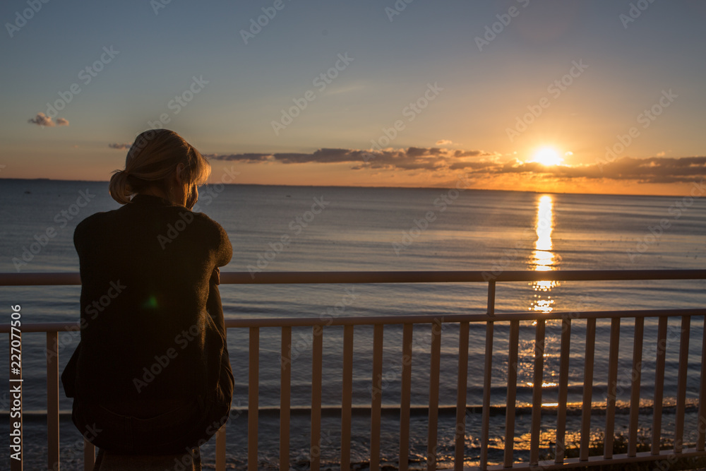 Woman looking at dramatic sunset at the sea