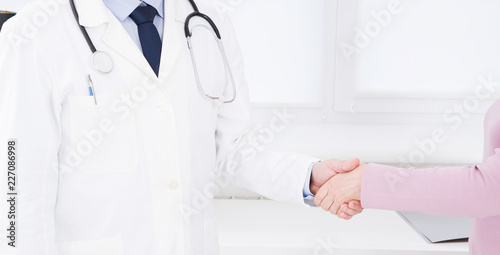 hand of doctor shakes female arm his patient in clinic  medical office. Healthcare concept  health insurance