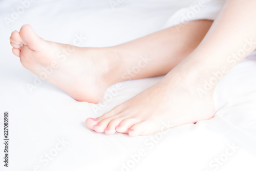 Woman's bare feet on bed in light room.Beautiful and elegant female foot .Spa, scrub and foot care concept.