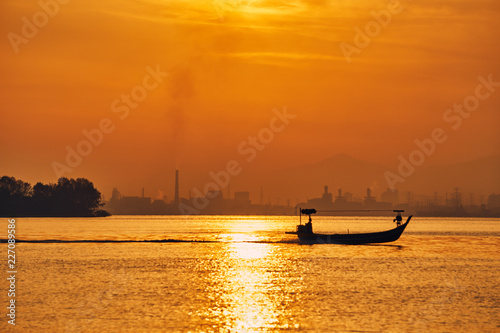  Fishing boat in the sea on the background of the sun rising over the city.