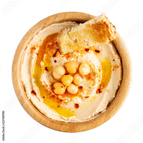 Classic chickpea hummus with olive oil and paprika served with bread in wooden bowl isolated on white